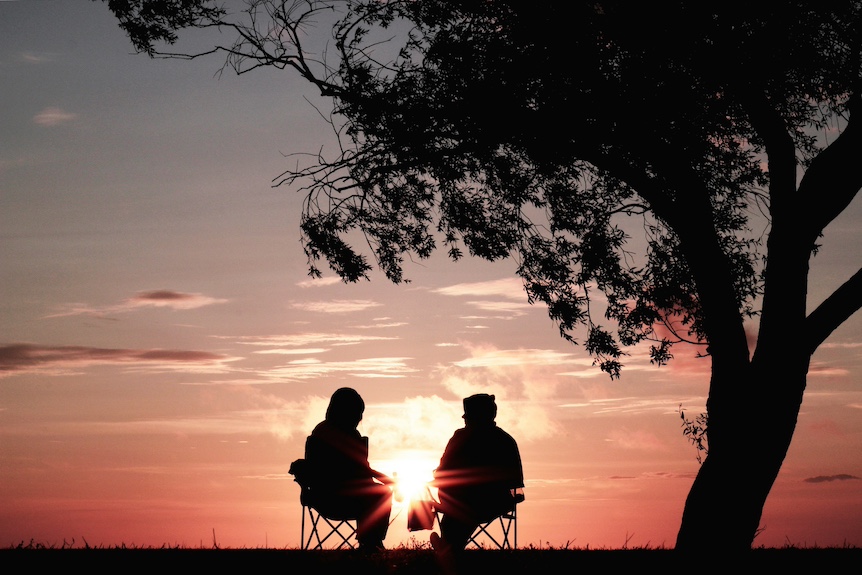 photo montrant 2 personnes assises devant un coucher de soleil, illustration des bienfaits d'une nouvelle vie, gérée grâce à un accompagnement retraite